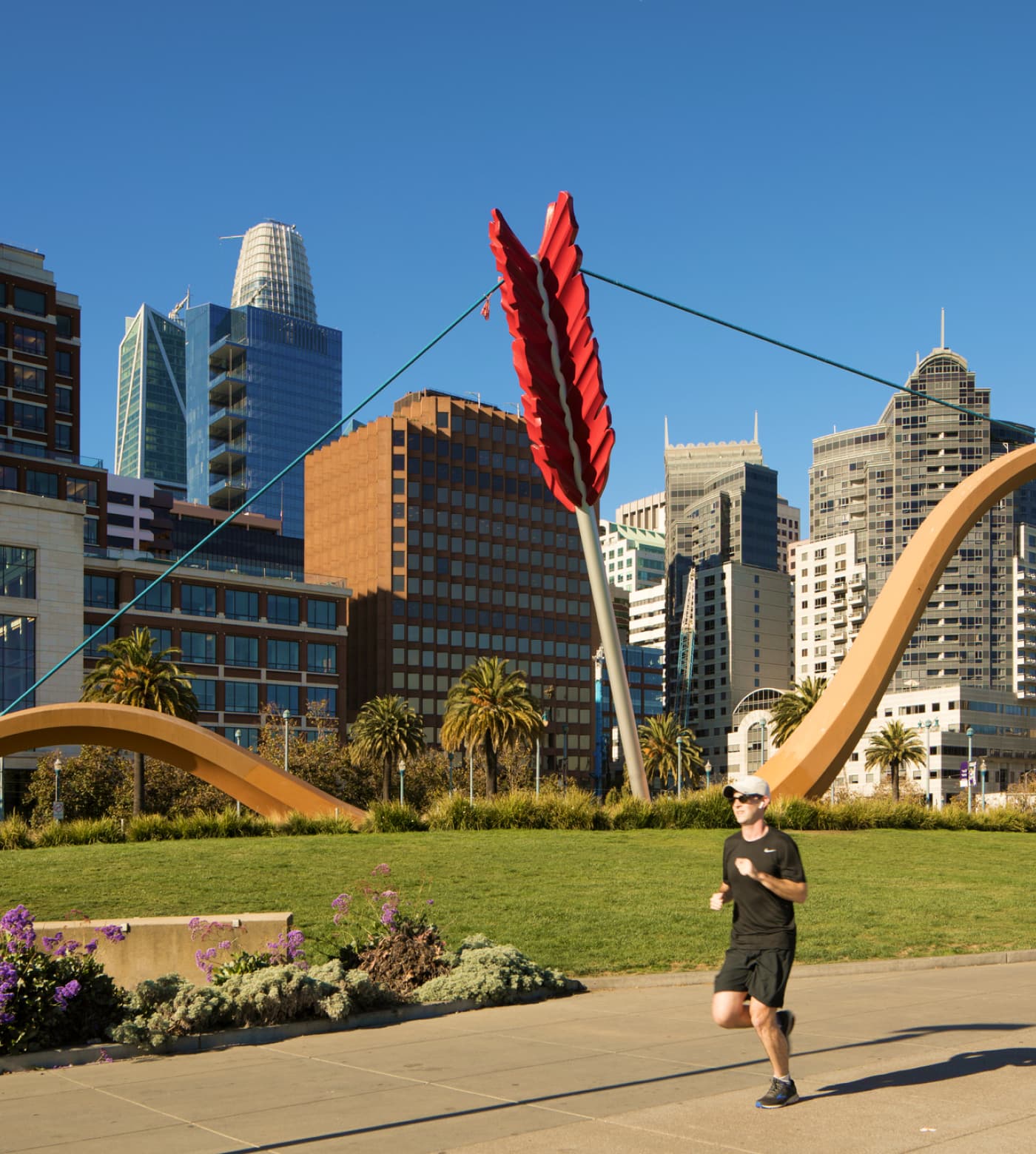 A man jogging past Cupid's Span sculpture in Rincon Park
